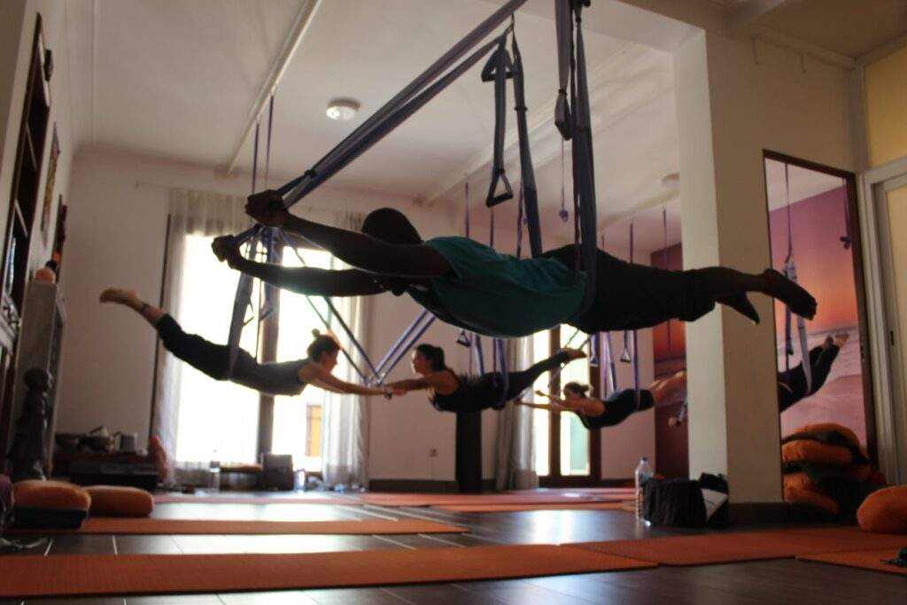 grupo practicando yoga aéreo con columpio de estribos en formación IEYA