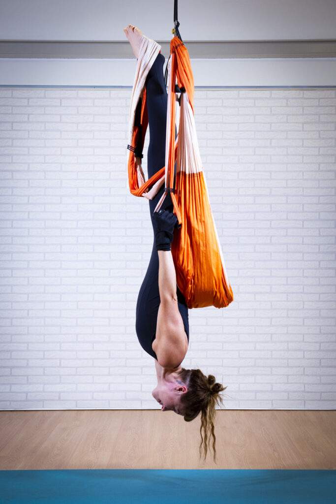 práctica individual de yoga aéreo con columpio realizando postura técnica avanzada