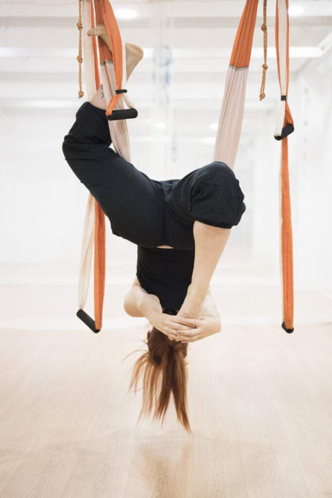postura invertida de yoga aéreo en columpio durante práctica avanzada