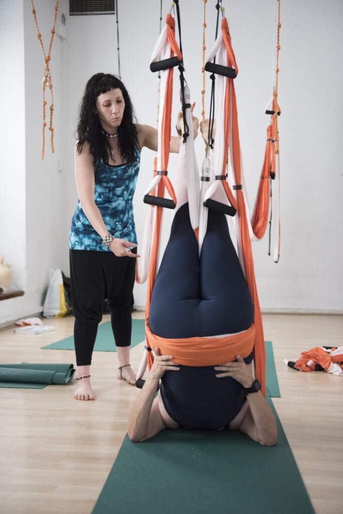 Práctica de yoga aéreo restaurativo en columpio durante formación IEYA