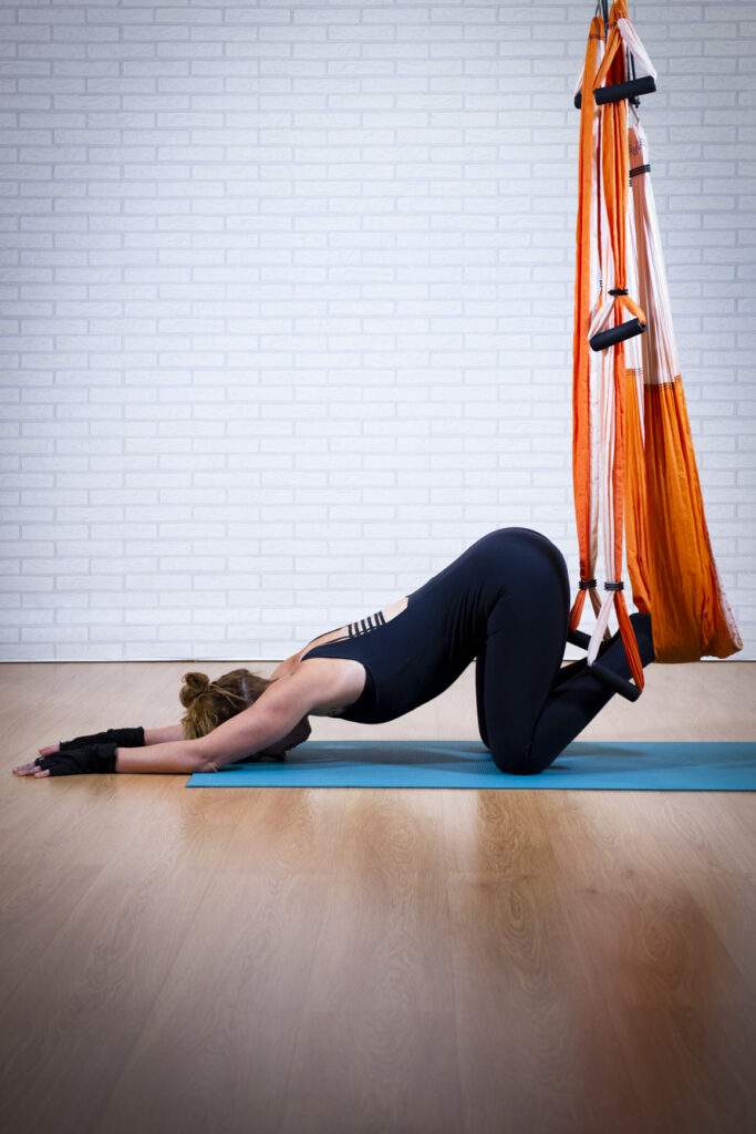 postura de yoga aéreo en suspensión con enfoque en relajación y respiración